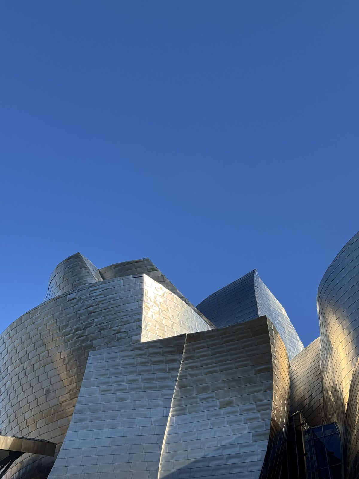 The titanium curves of the Guggenheim Museum against a deep blue sky