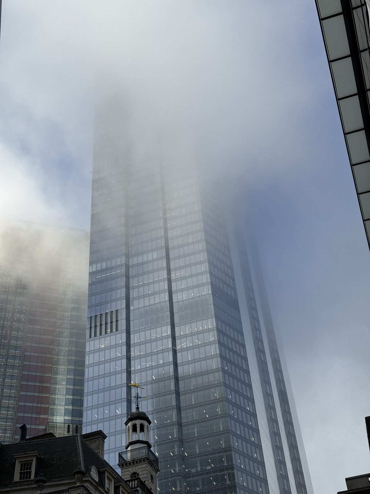 A glass tower disappearing into fog