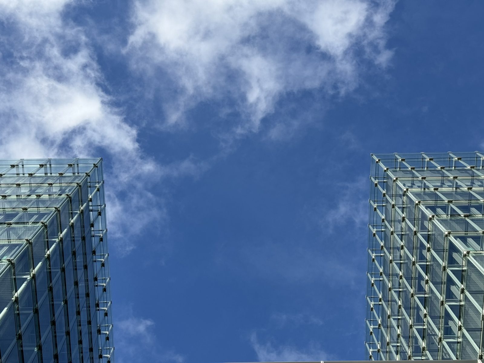 Two glass blocks against a sky of broken cloud