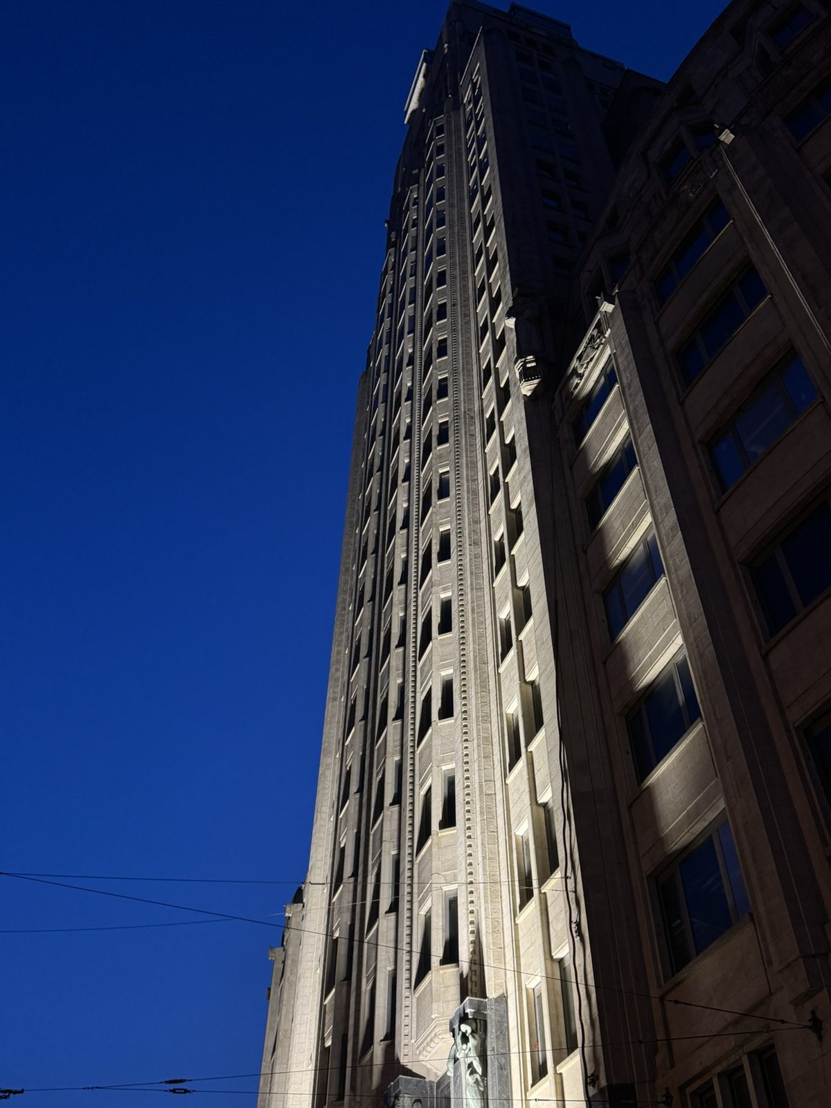 A stone-clad tower against a deep blue sky, lit from the side