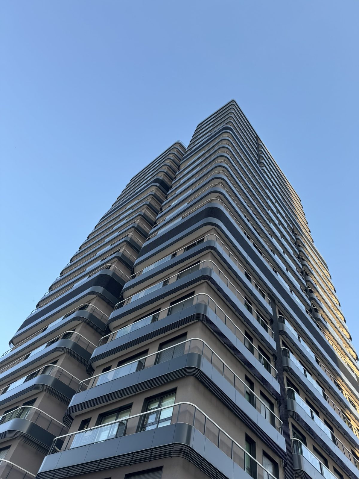 A high-rise with rounded balconies against a blue sky