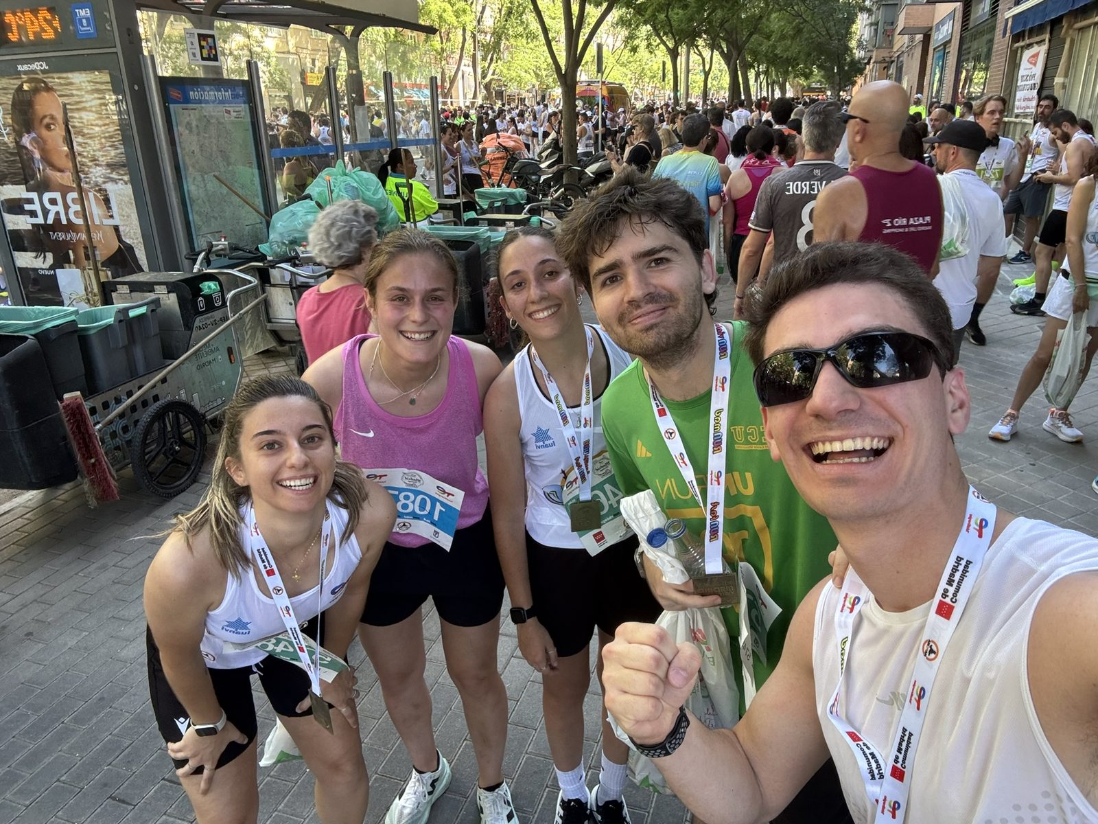 A group selfie of runners with race bibs on a busy street