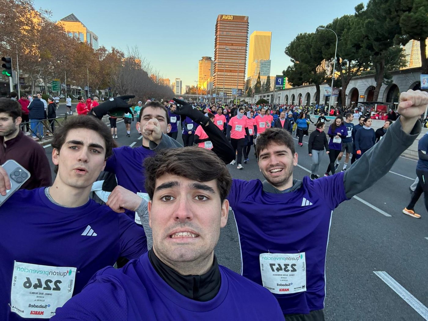 A group selfie of runners in matching purple race shirts on a city course
