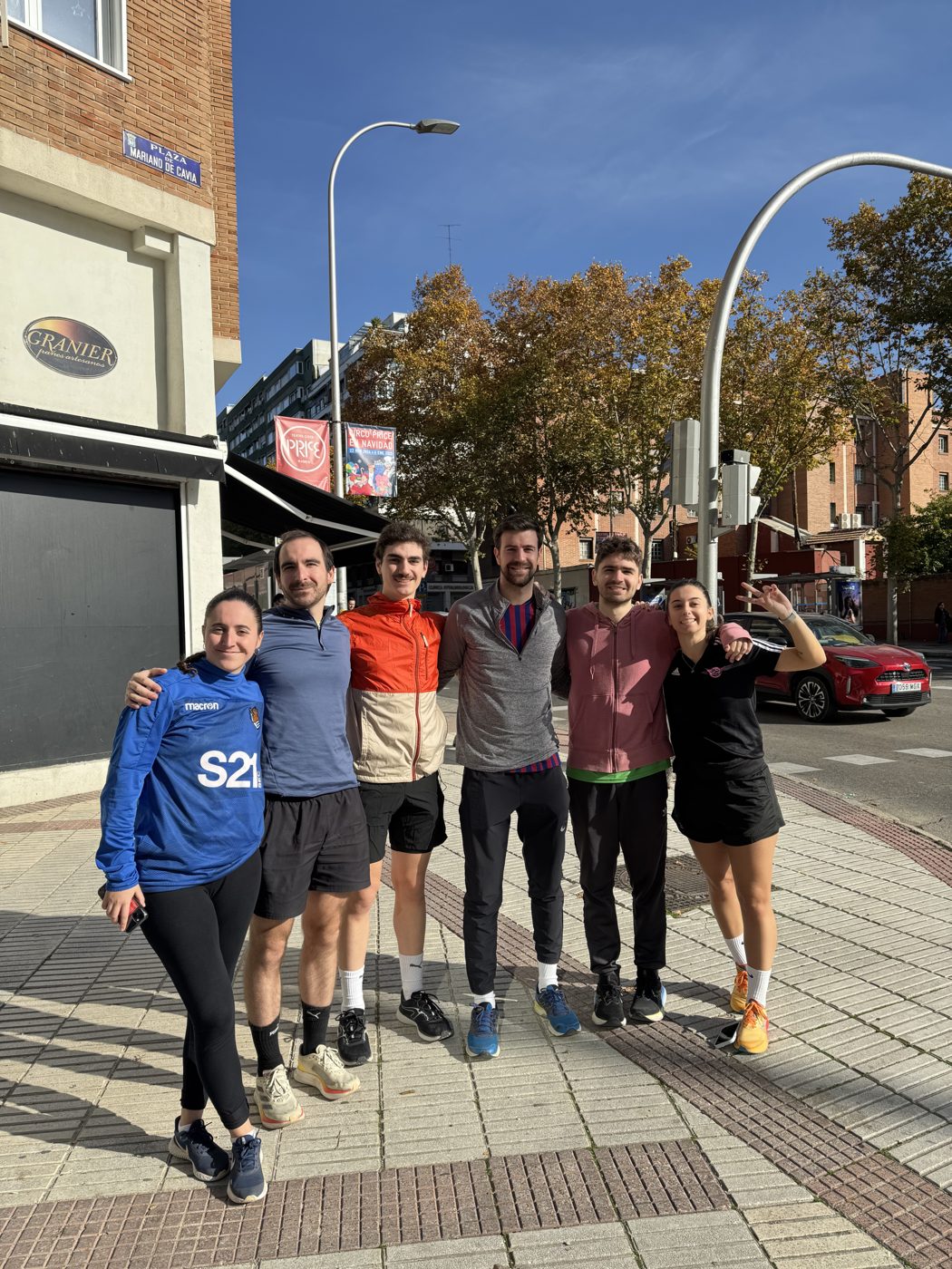 Six friends in running gear on a sunny street after a run